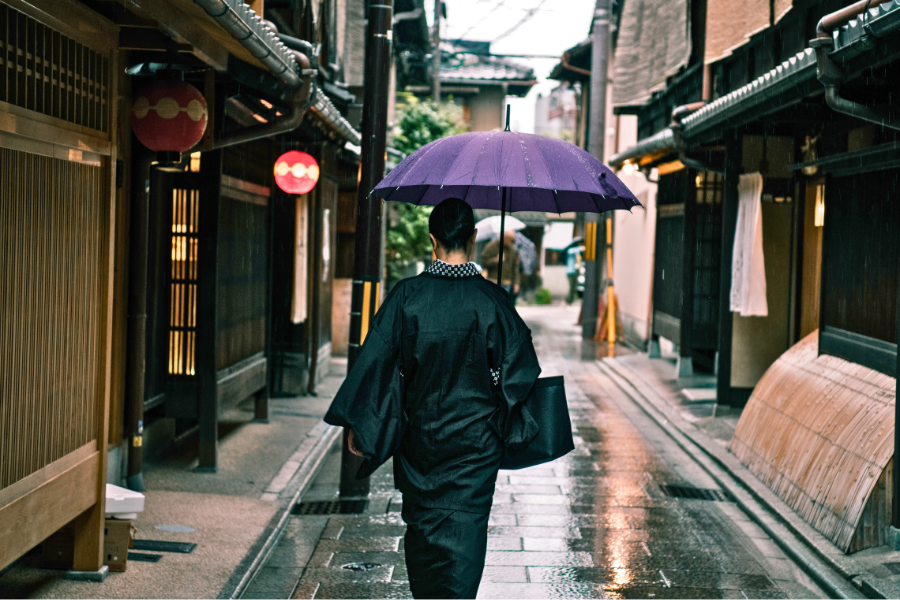 雨の古都を歩く着物姿の女性